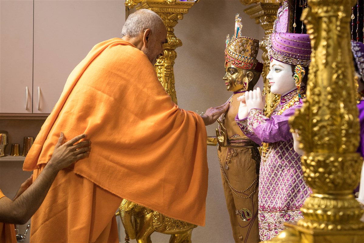 Swamishri puts the finishing touches of the chandan adornments on Harikrishna Maharaj