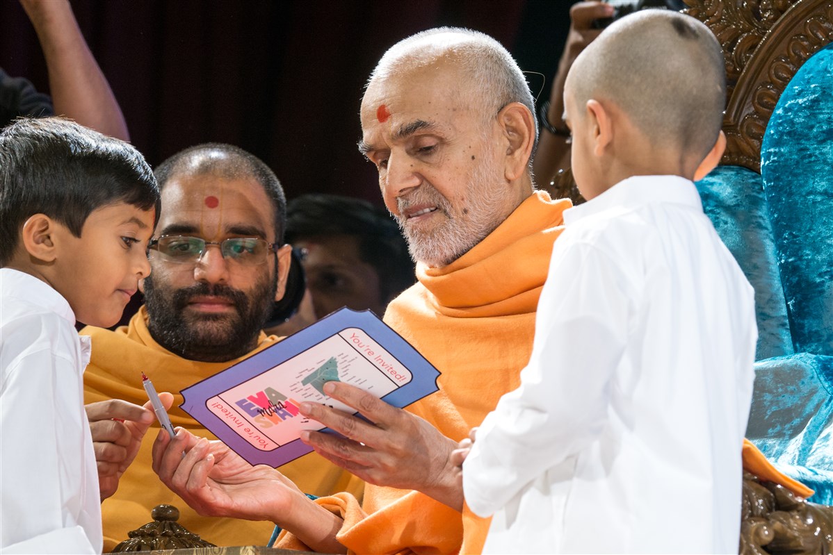 Two children present Swamishri with an invitation to the Bal-Balika Din