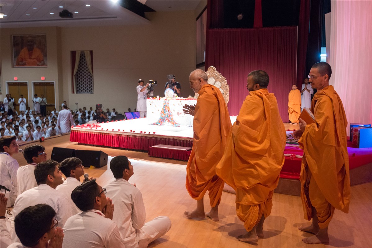 Swamishri folds his hands to youths singing in puja