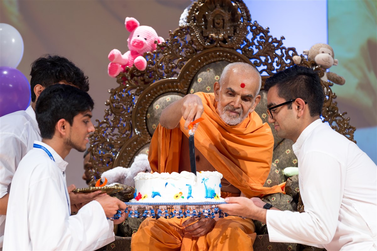 Swamishri cuts a cake for the children