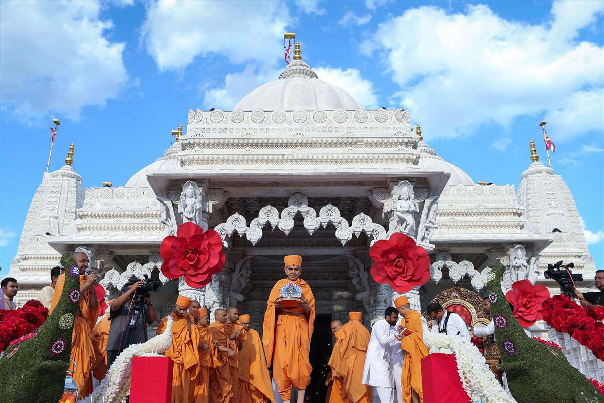 Swamishri greets devotees while holding Shri Harikrishna Maharaj