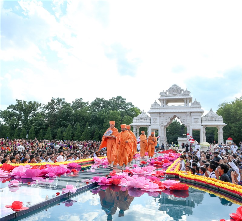 Swamishri greets devotees while holding Shri Harikrishna Maharaj