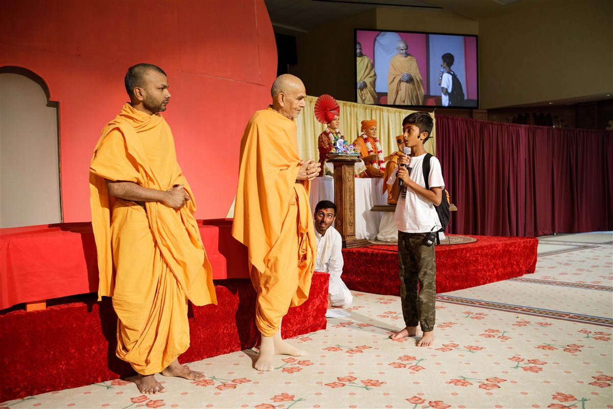 A child interacts with Swamishri during the Bal-Balika Din