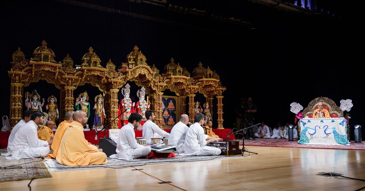 Swamis and devotees sing during Swamishri's puja