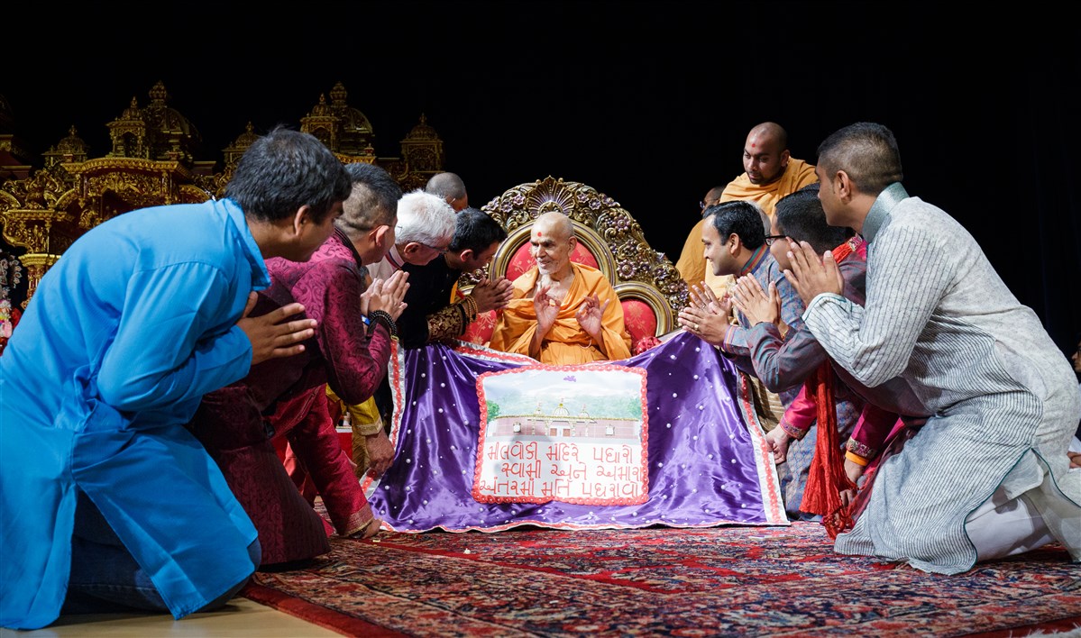 Swamishri is offered a shawl by devotees from Milwaukee
