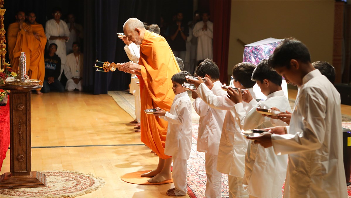 Swamishri performs the evening arti with children, 18 July 2017