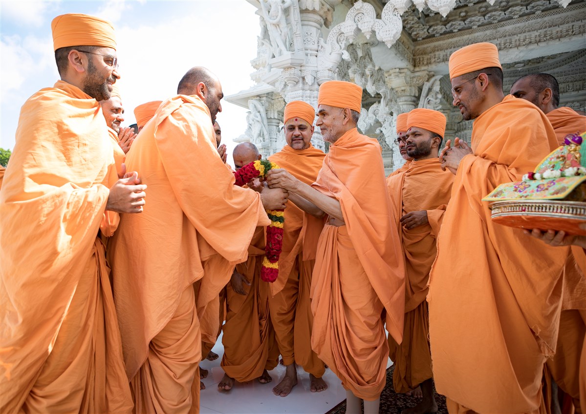 Pujya Priyasevadas Swami offers a garland as Swamishri departs for Toronto, Canada, 19 July 2017