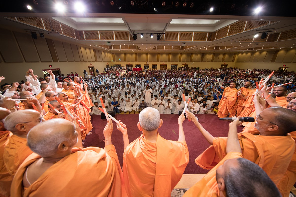 Mahant Swami Maharaj joins hands with swamis and youths in a gesture of unity
