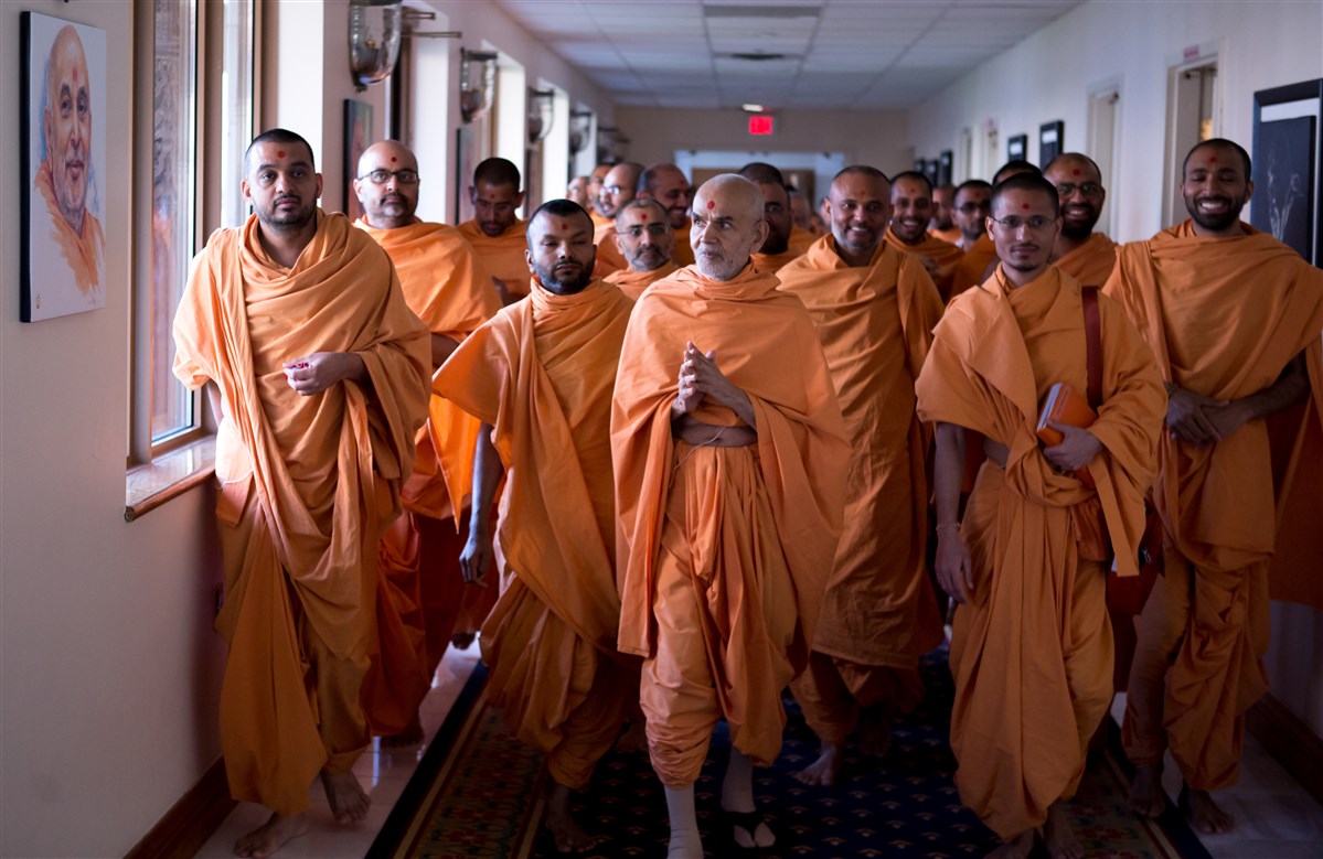 Swamishri folding his hands to a painting of Pramukh Swami Maharaj