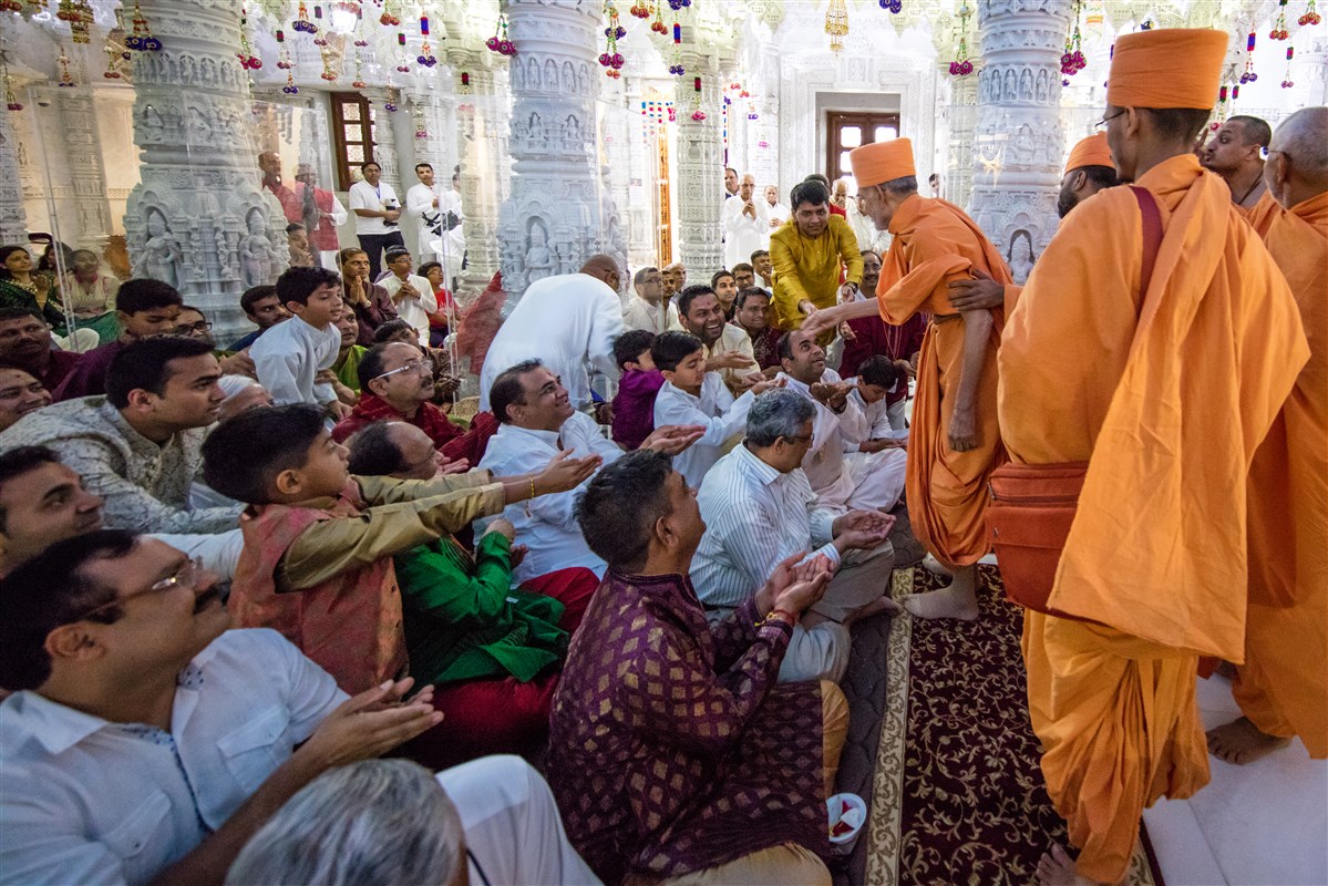 Swamishri blesses devotees by showering rice grains