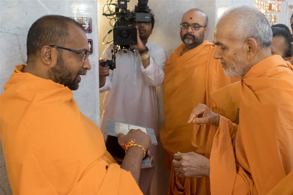 Swamishri views a model of the isolator units used to protect the Mandir against seismic activity