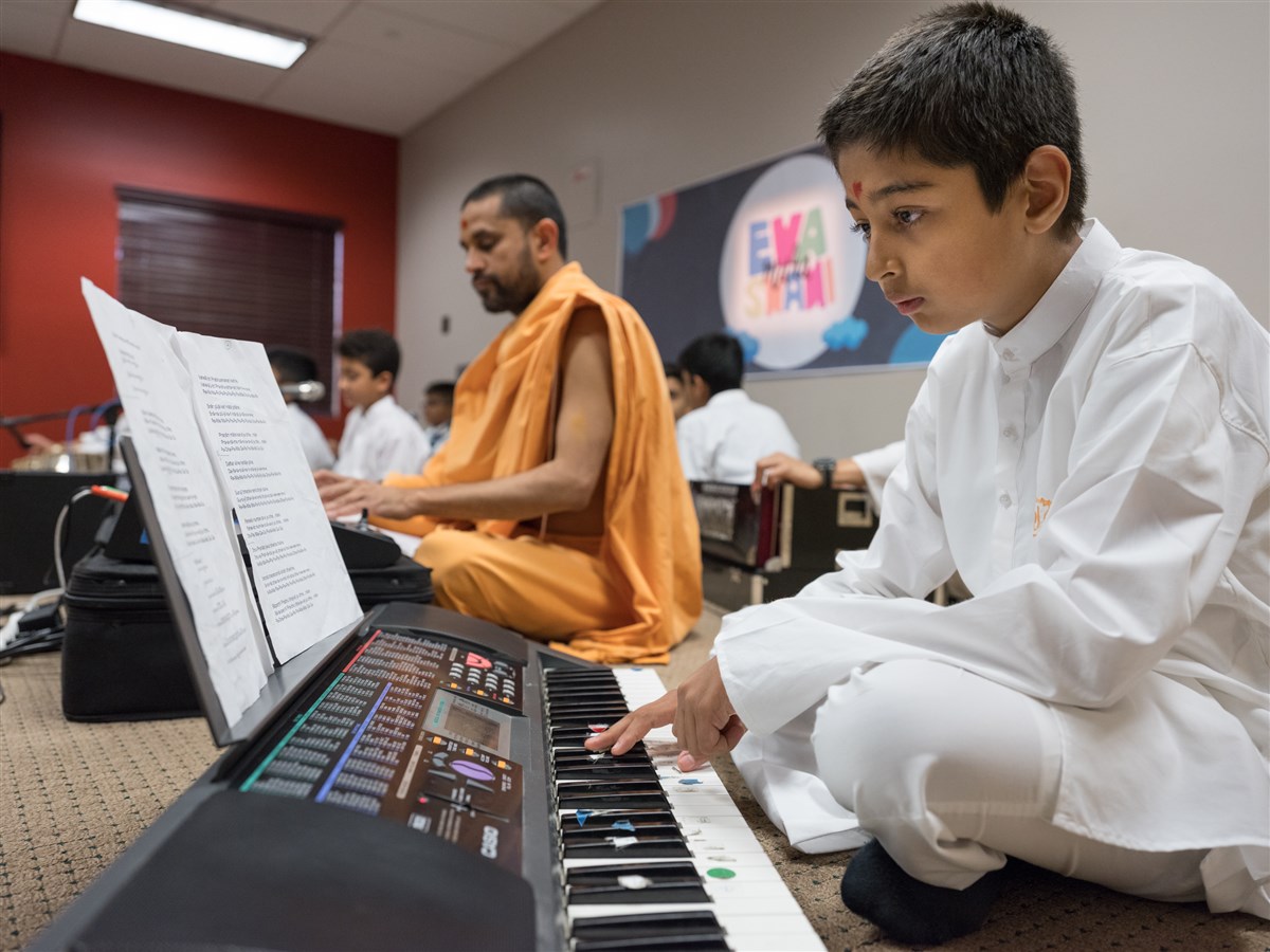 A child plays the keyboard in Swamishri's puja