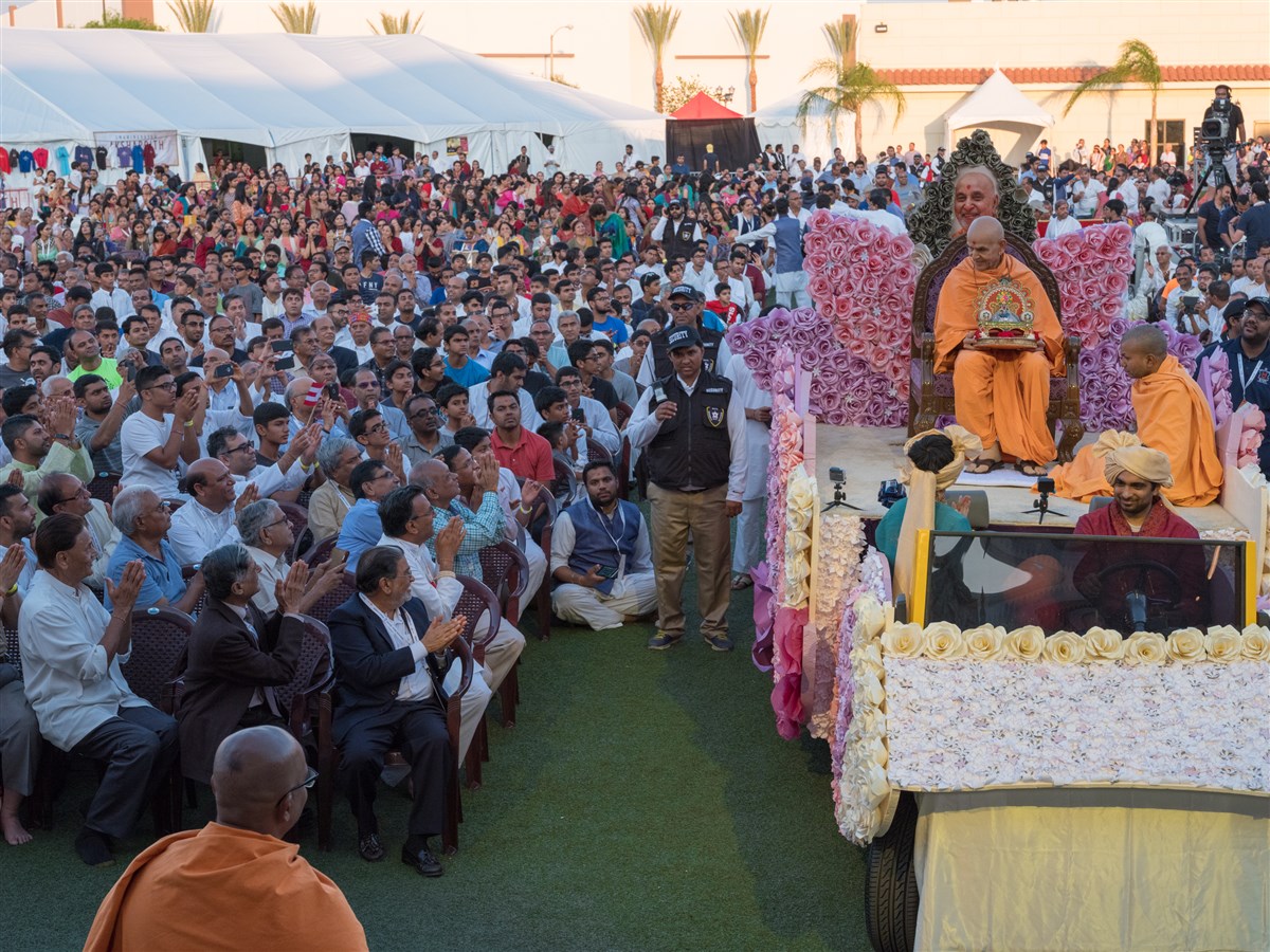 Swamishri arrives to the evening assembly on a rath 