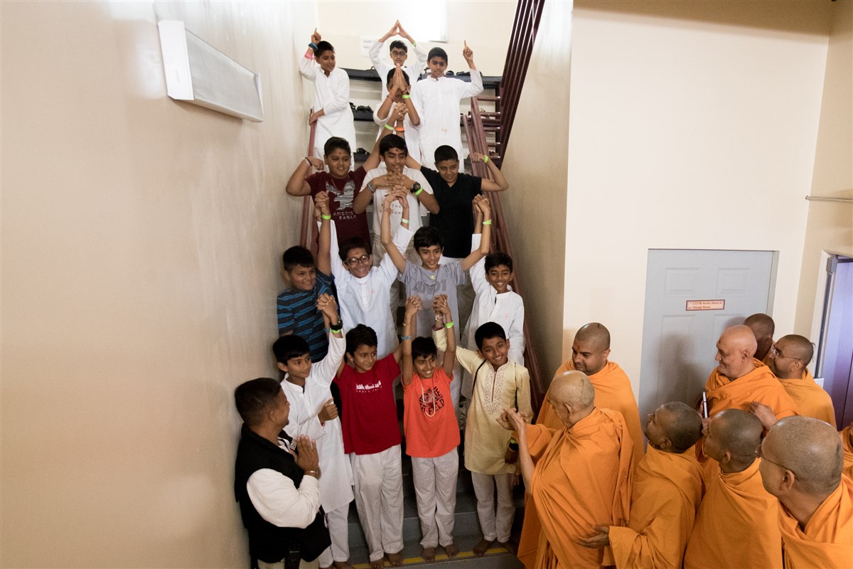 Children hold hands in front of Swamishri as a gesture of unity