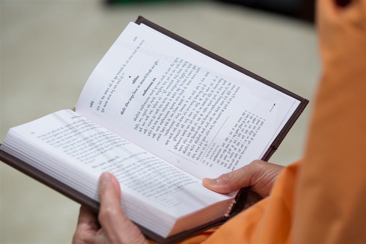 Swamishri reads from 'Purushottam Bolya Prite' during the assembly