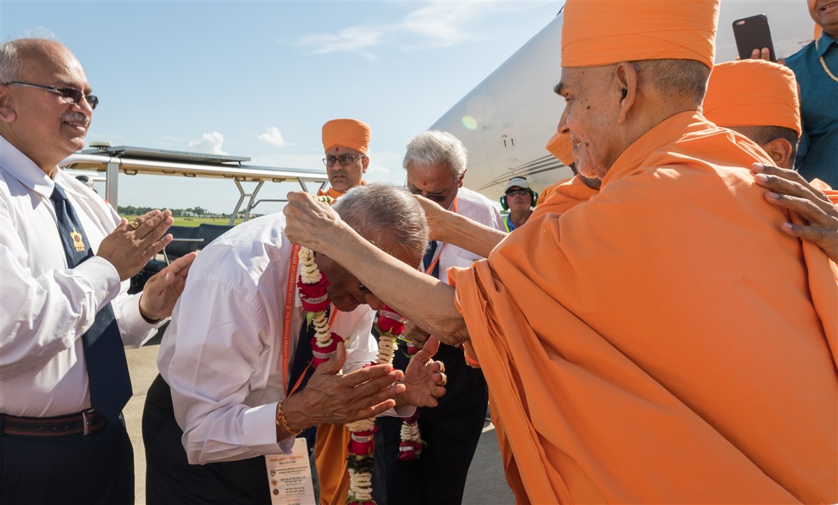 Param Pujya Mahant Swami Maharaj garlands a devotee upon arriving in Houston, TX