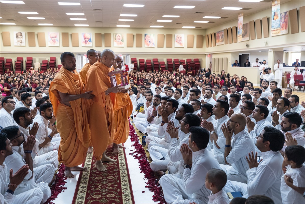 Swamishri greets youths while holding Shri Harikrishna Maharaj