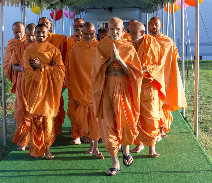 Swamishri walks after puja with folded hands