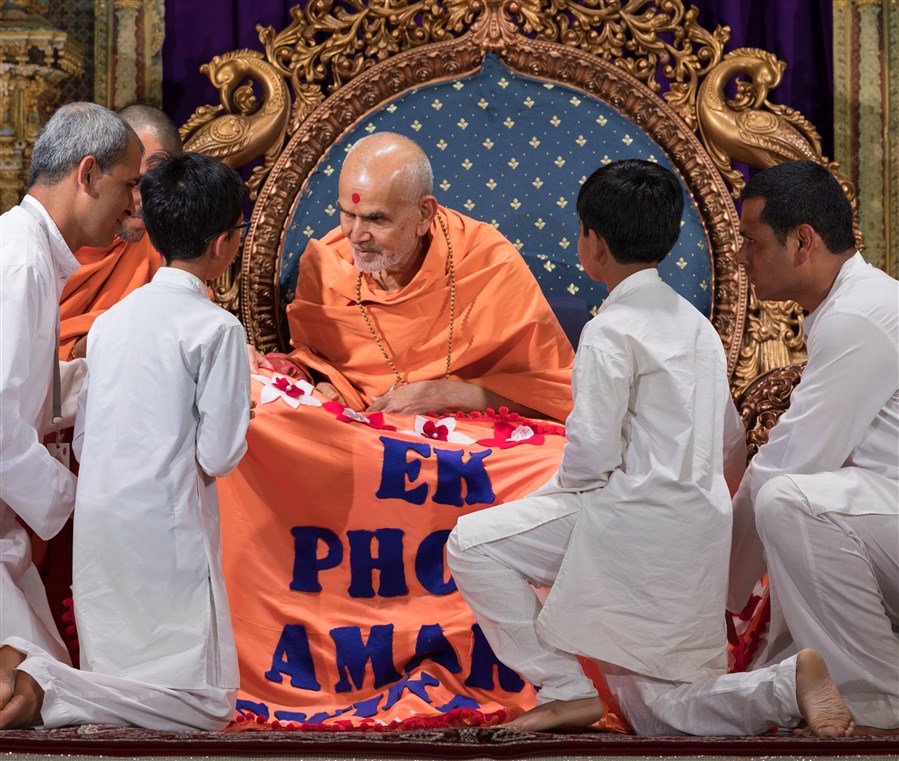 Swamishri is offered a shawl by devotees
