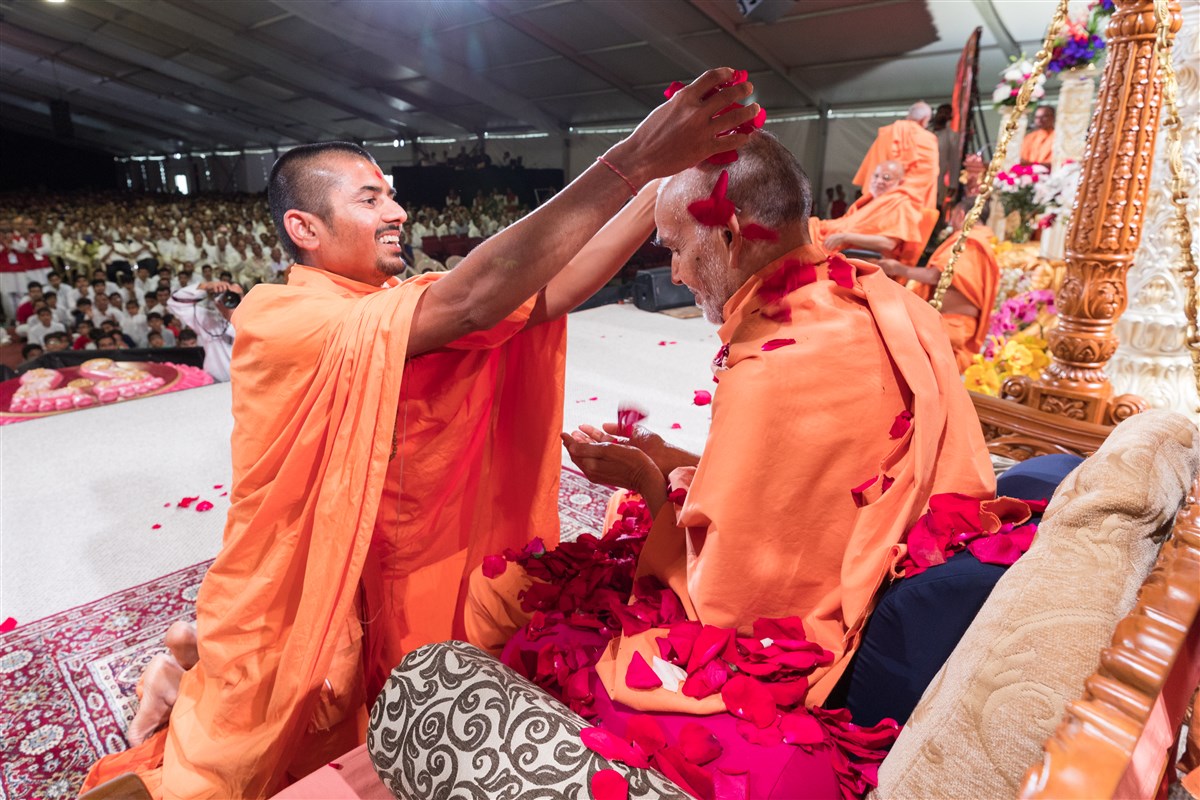 Pujya Shwetmunidas Swami showers Swamishri with flowers, 19 August 2017
