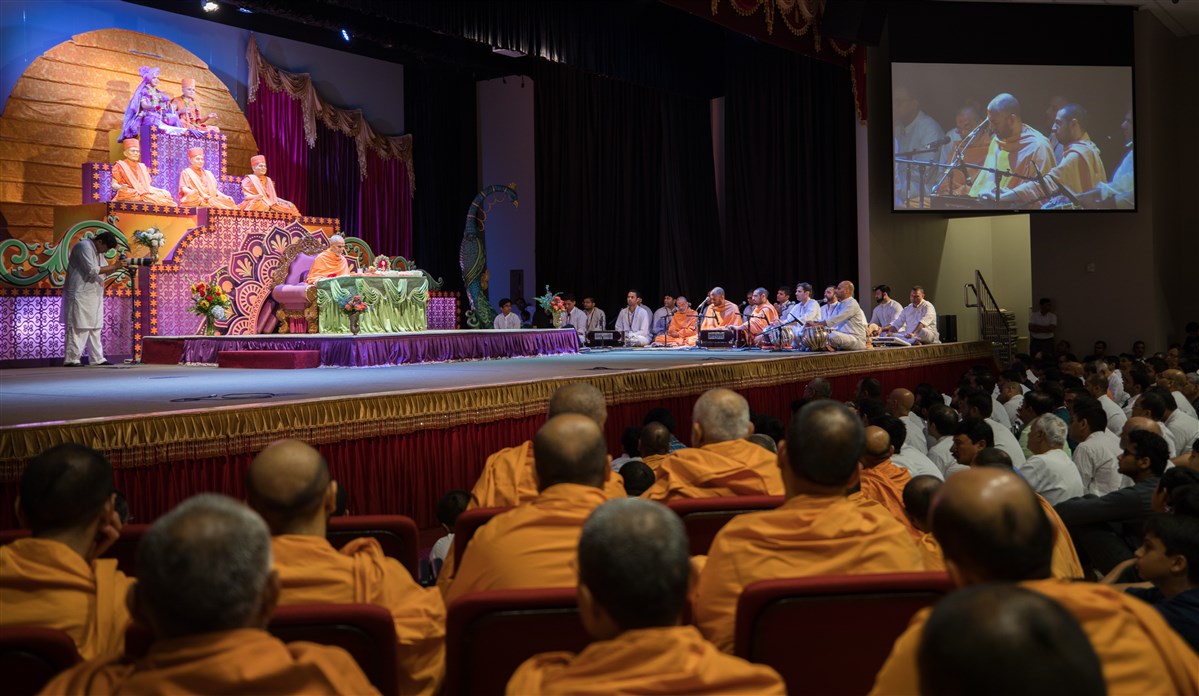 Swamis and devotees sing kirtans before Swamishri during his puja
