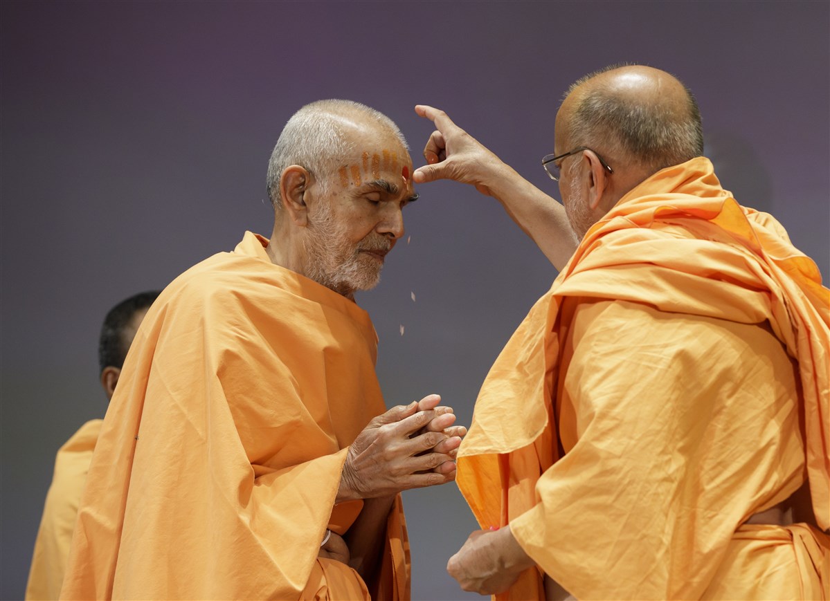 Pujya Ishwarcharan Swami applies chandlo on the forehead of Swamishri