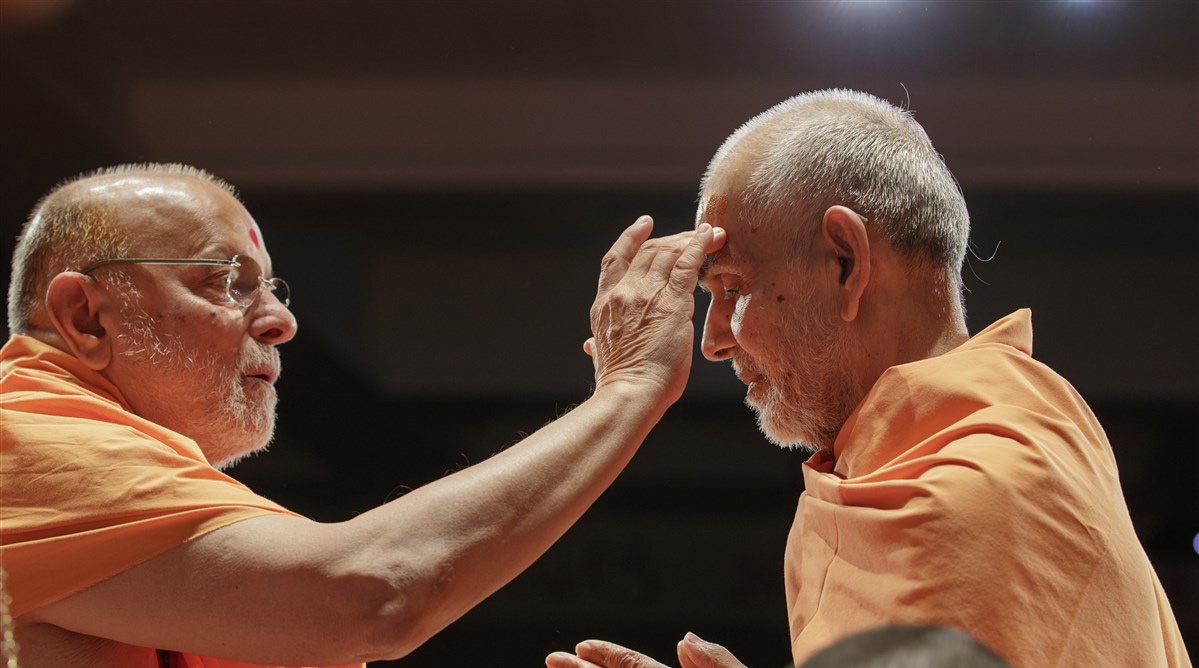 Pujya Ishwarcharan Swami performs chandan archa on the forehead of Swamishri