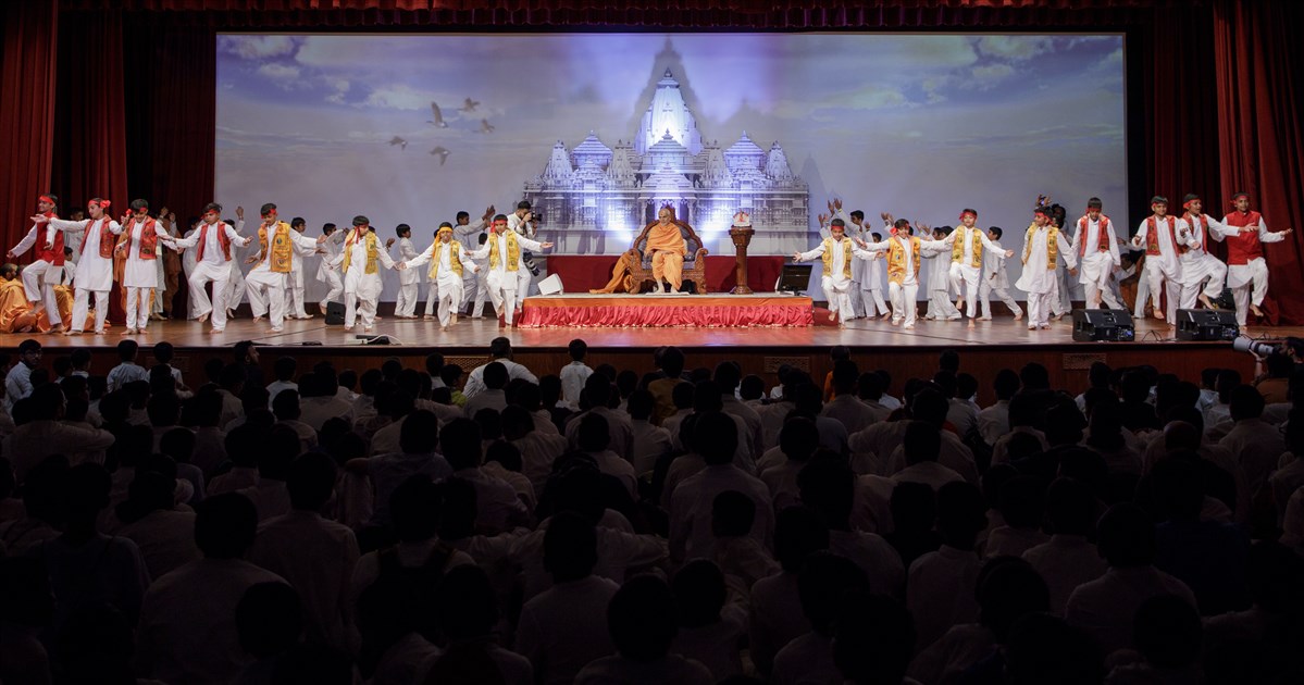 Youths welcome Swamishri to the evening assembly with a vibrant dance