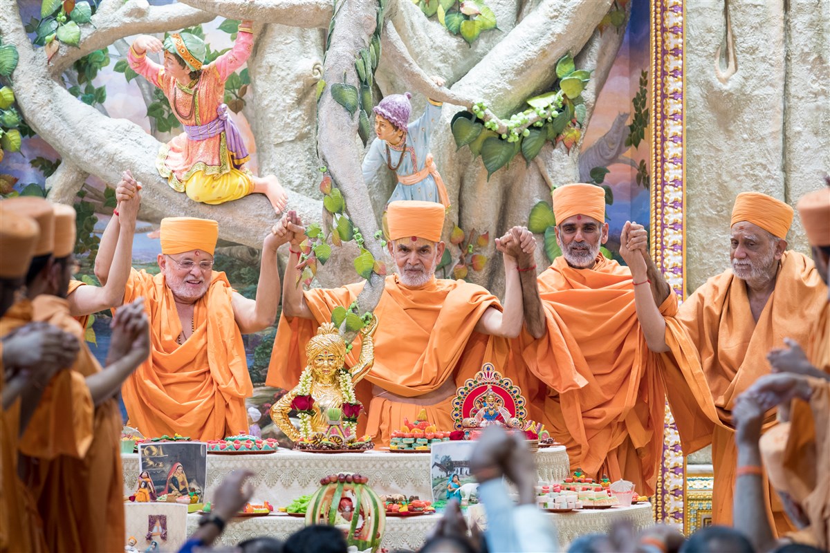 Swamishri and swamis joins hands in a gesture of unity