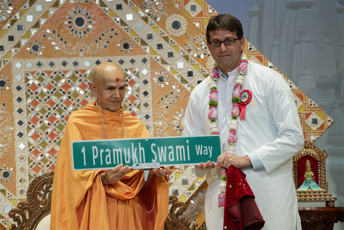 New Castle County Executive Matthew Meyer presents the new street sign to Swamishri