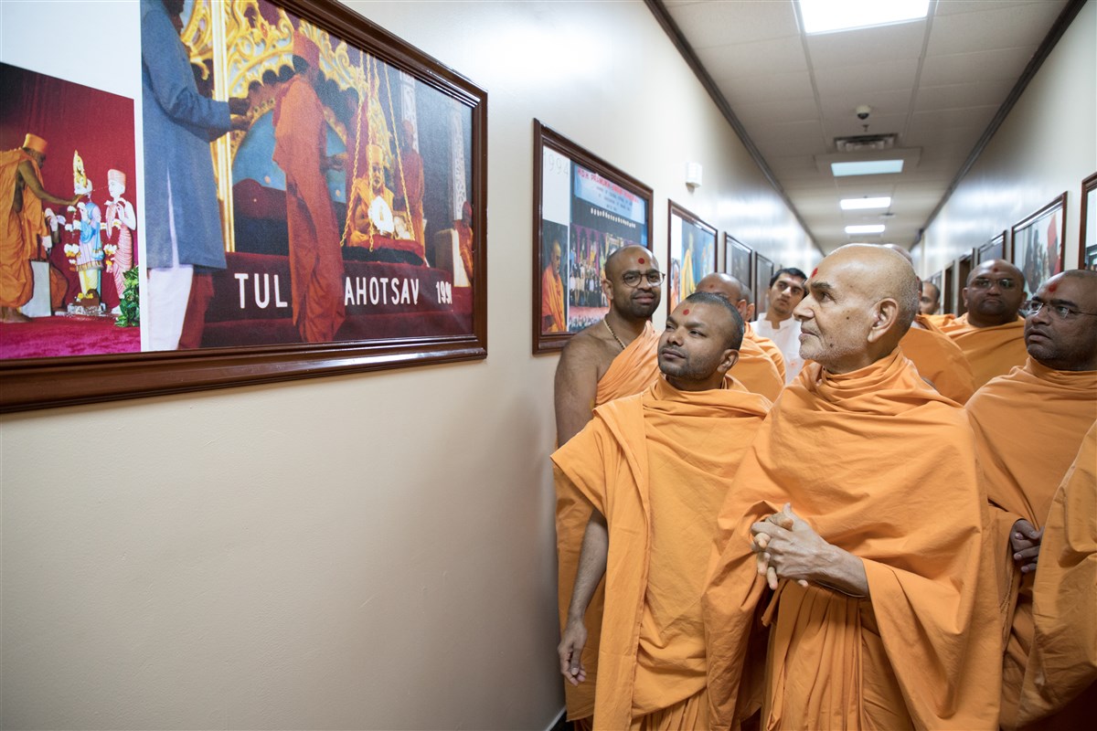 Swamishri views a photos of Brahmaswarup Pramukh Swami Maharaj being honoured in the Platinum Tula Mahotsav in Edison, New Jersey in 1991