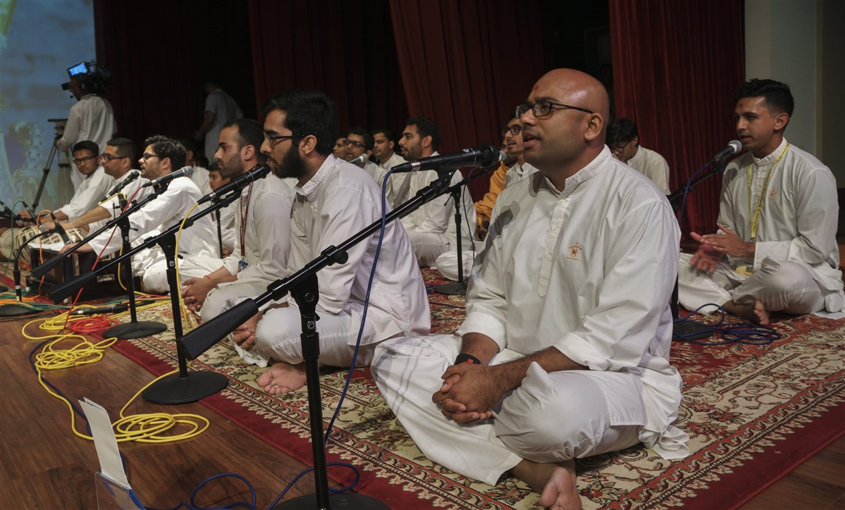 Youths sing kirtans before Swamishri during puja