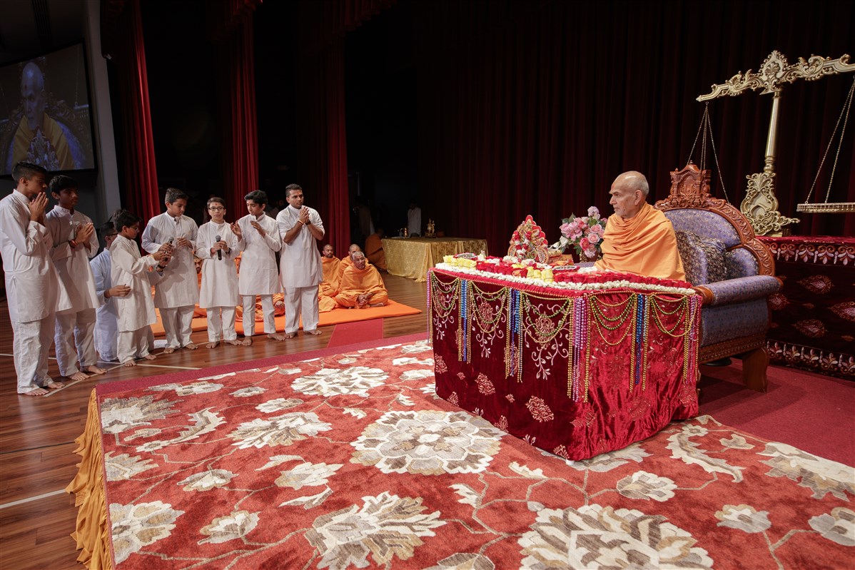 Children recite shlokas before Swamishri during puja