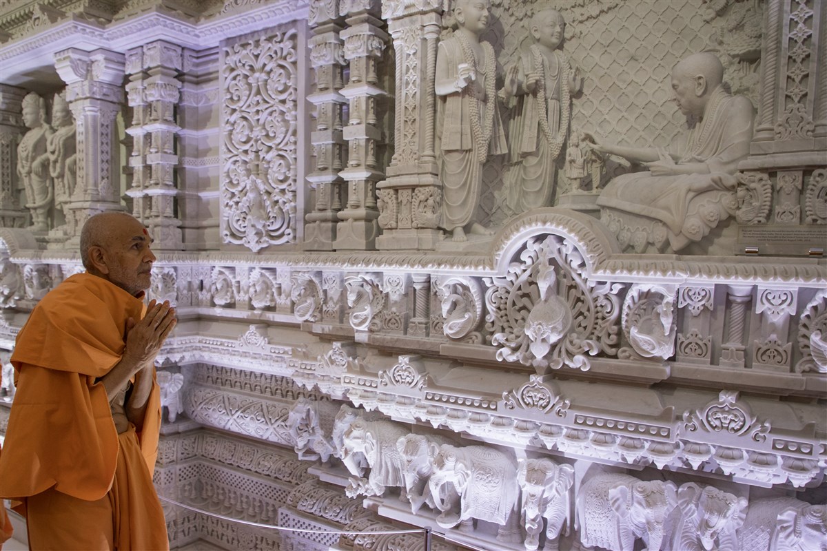 Swamishri engrossed in darshan of murti depicting consecration ceremony done by Pramukh Swami Maharaj, 18 September 2017