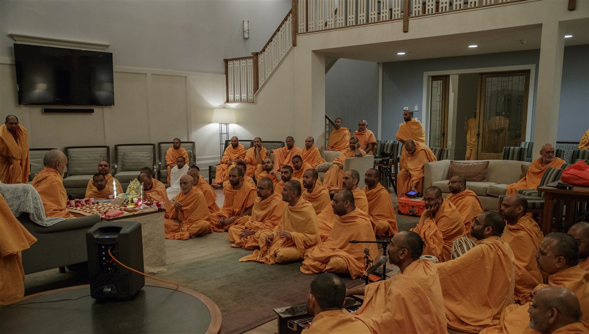 Swamis sing kirtans before Swamishri during puja