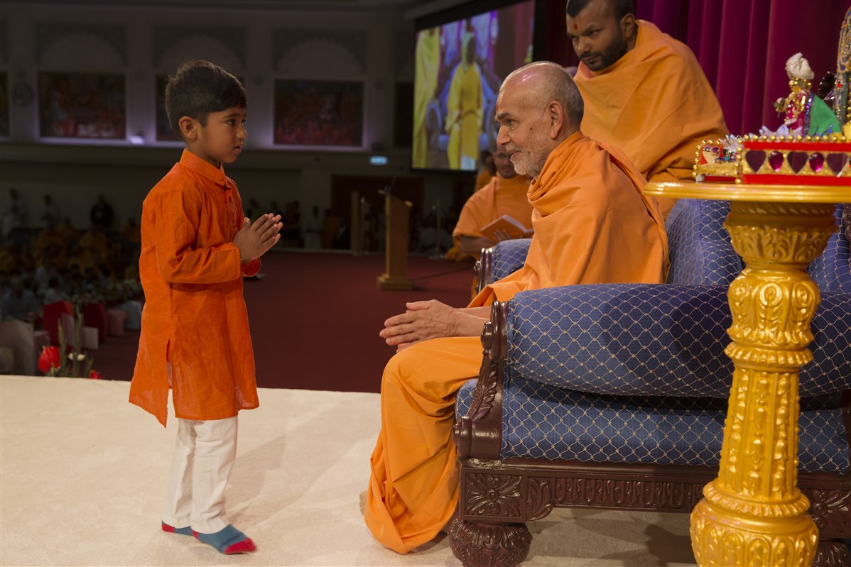 A child receives blessings after performing during Swamishri's puja
