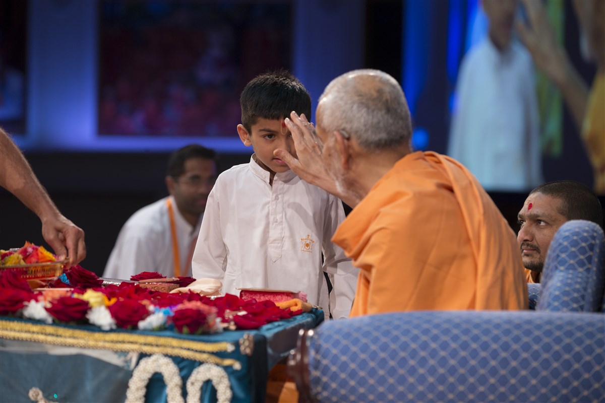 Swamishri blesses a child who recited scriptural quotations during the puja