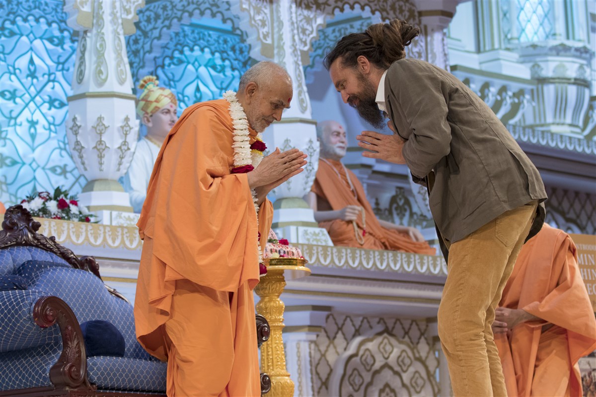 Dr Mallinson honours Swamishri with a garland and receives Swamishri's blessings