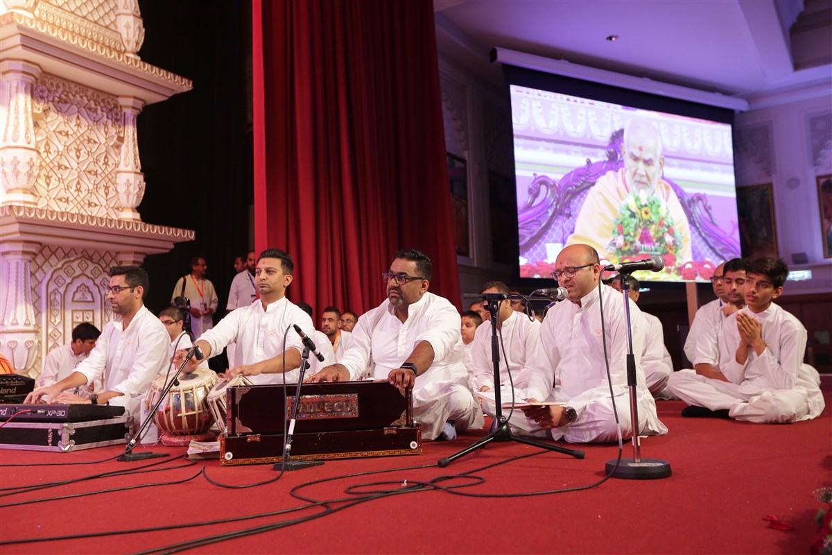 Swamis and devotees sing in Swamishri's puja