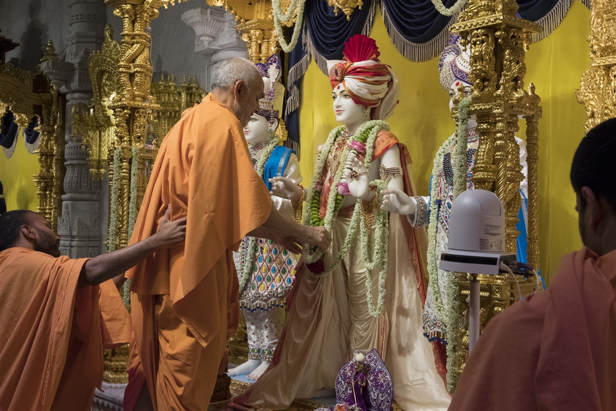Swamishri adjusts the adornments of the murtis