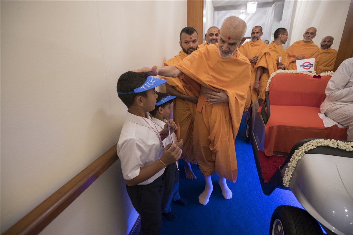 Swamishri blesses two children, posing as ticket masters