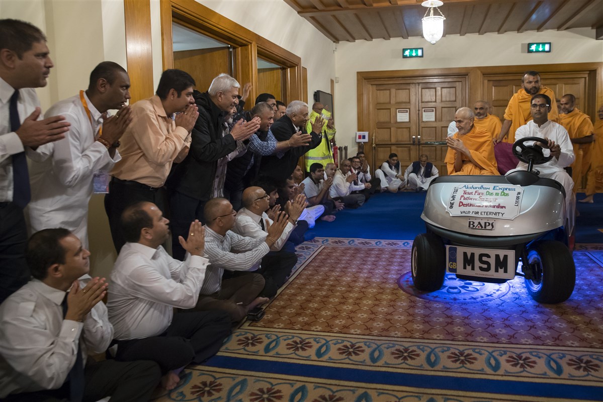 Swamishri greets devotees en route to the assembly hall