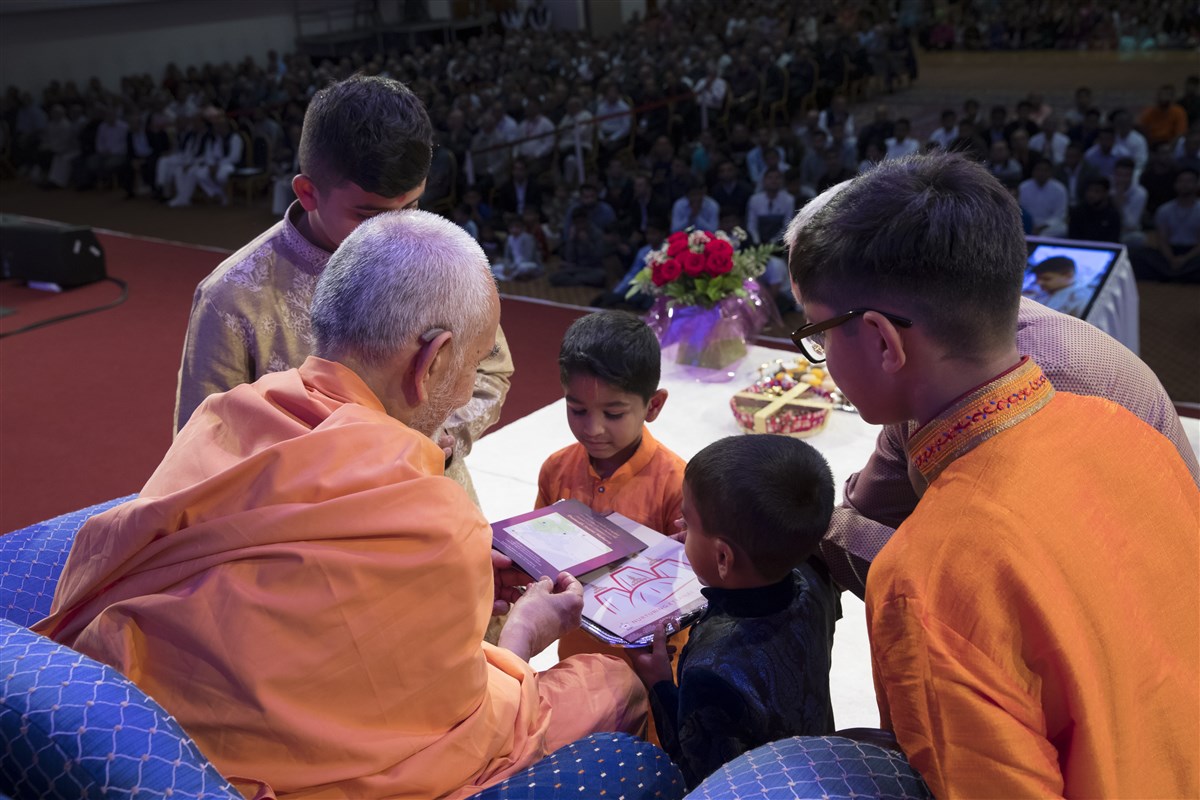 Children from East London present an invitation to Swamishri for the upcoming East London Mandir Pratishtha Mahotsav
