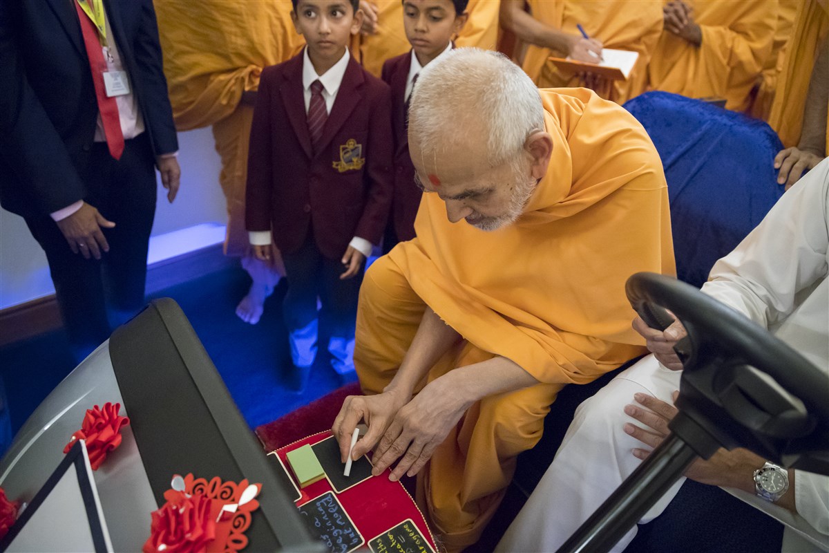 Swamishri inscribes an inspiring message for the pupils with a piece of chalk