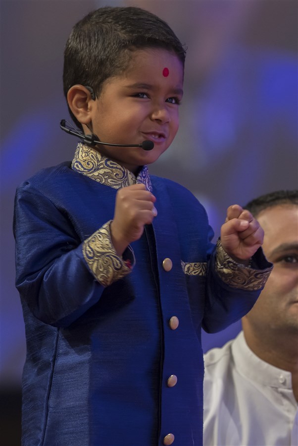 A young pupil of The Swaminarayan School presents a prasang from the life of Yogiji Maharaj before Swamishri
