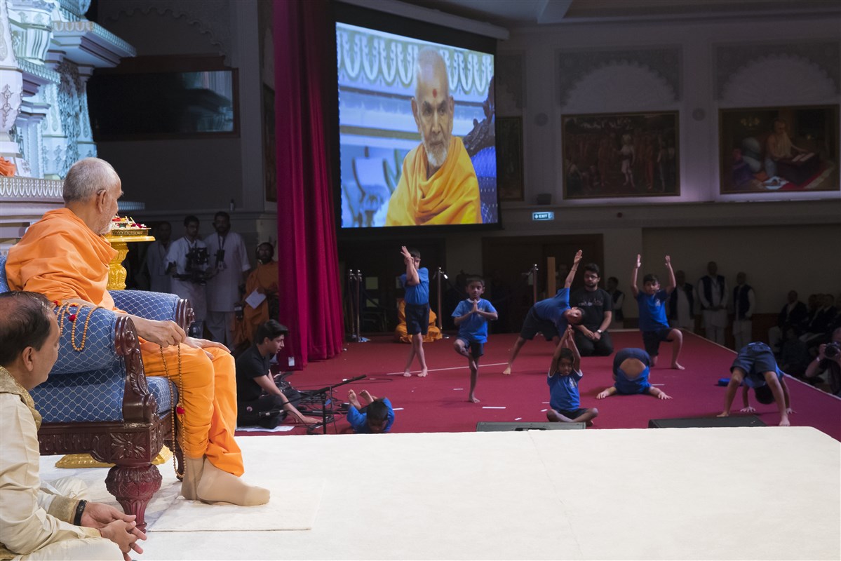 Young pupils perform yoga exercises before Swamishri