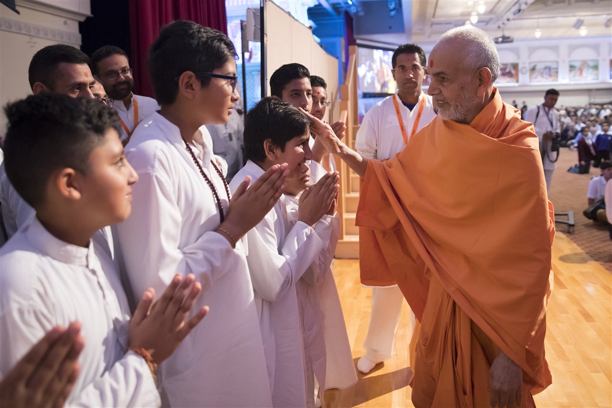 Swamishri blesses children as he departs the hall