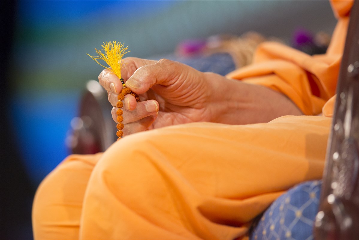 Swamishri turns a mala during the evening assembly