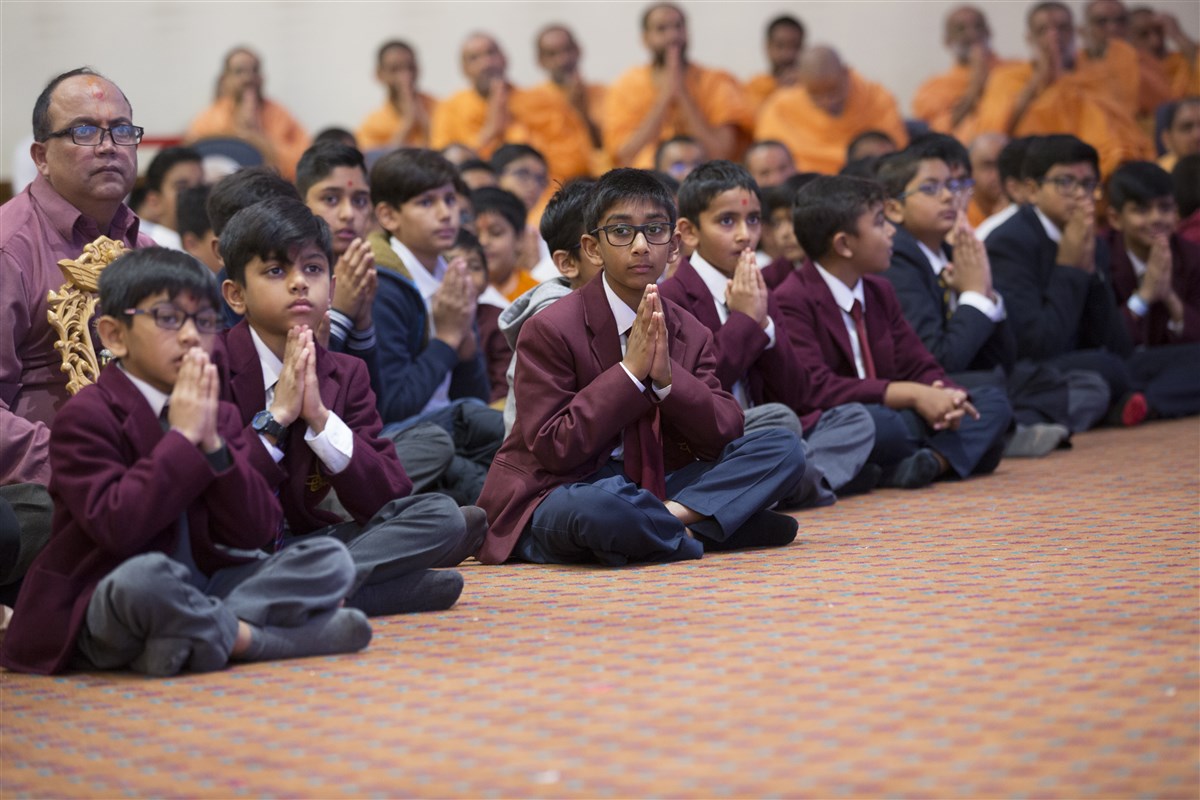 Pupils from The Swaminarayan School greet Swamishri with folded hands