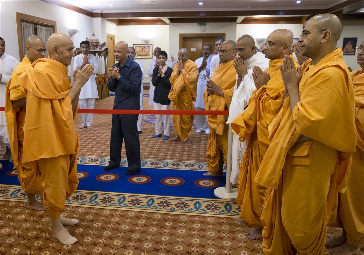 Param Pujya Mahant Swami Maharaj greets swamis and devotees with folded hands as he leaves his room